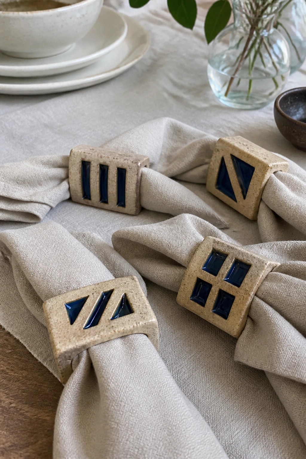 Ceramic napkin rings with blue geometric patterns on beige linen napkins