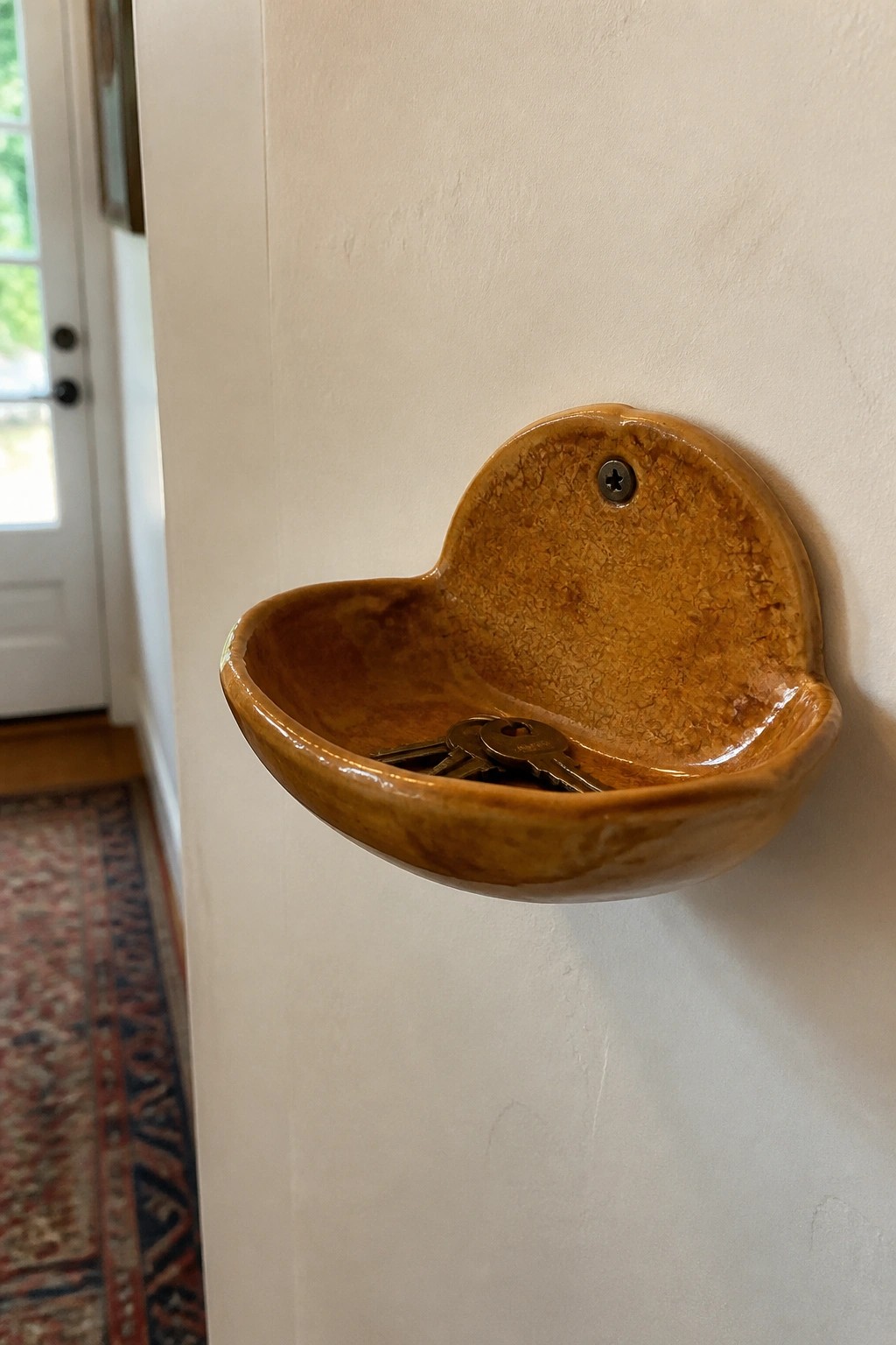 Brown glazed ceramic bowl mounted on white wall holding keys
