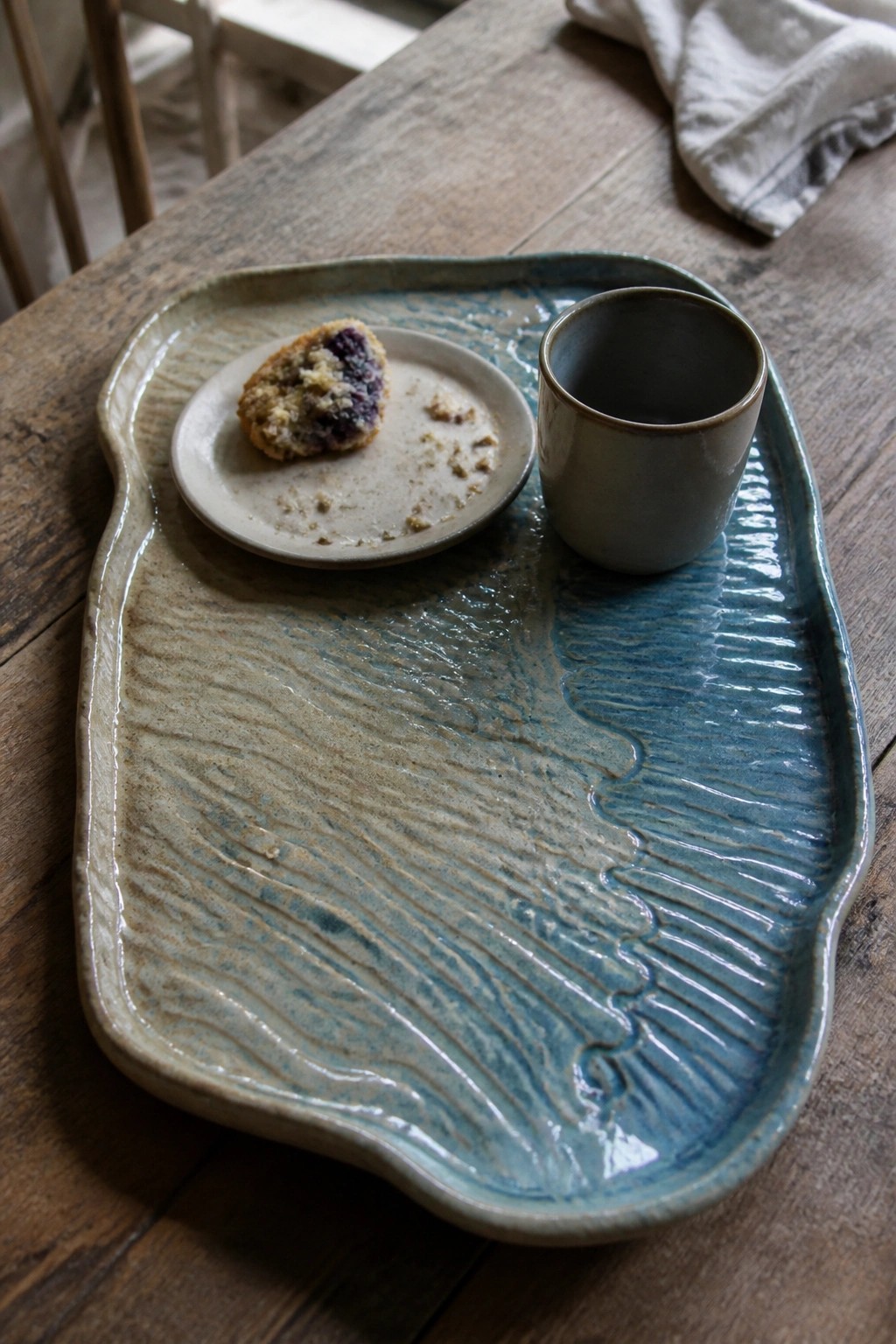 Blue ceramic tray with muffin plate and cup on rustic wooden table