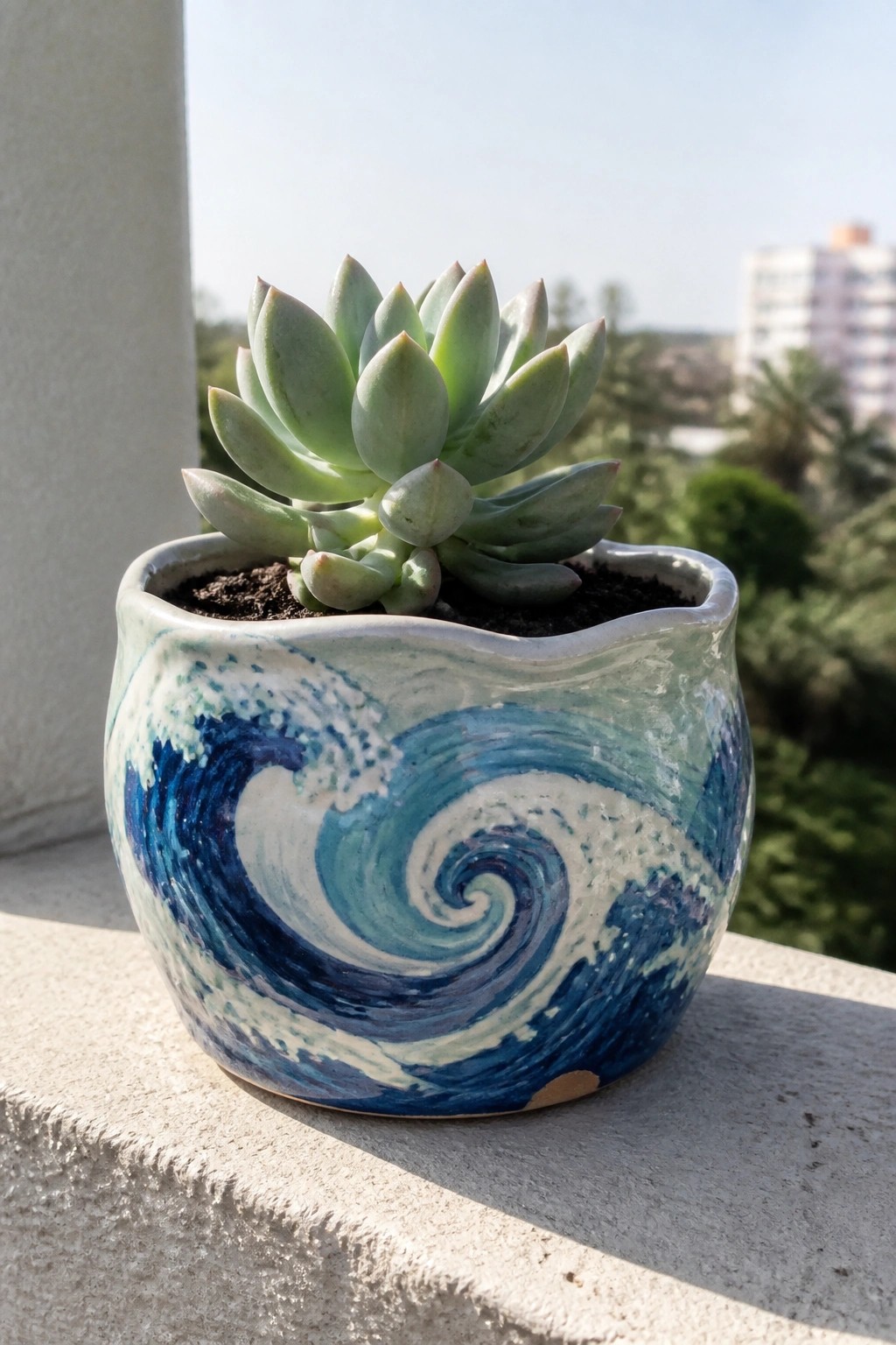 Green succulent in blue-and-white wave-swirl ceramic pot on stone ledge