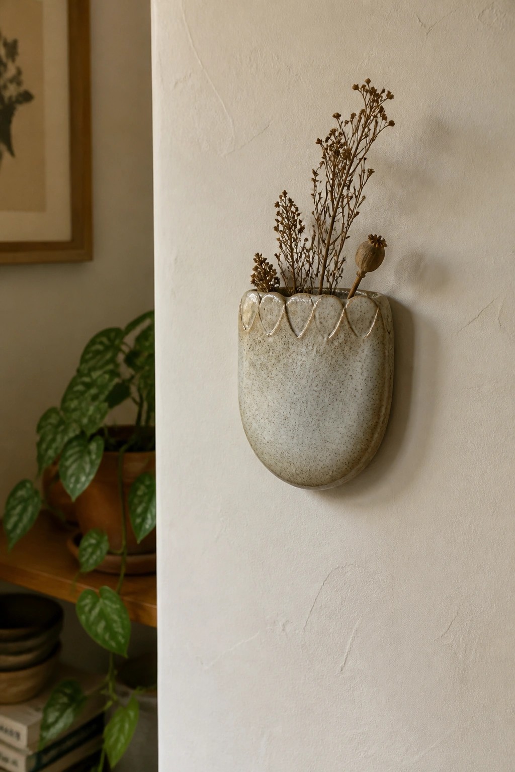 Speckled ceramic wall vase with dried botanicals on white textured wall