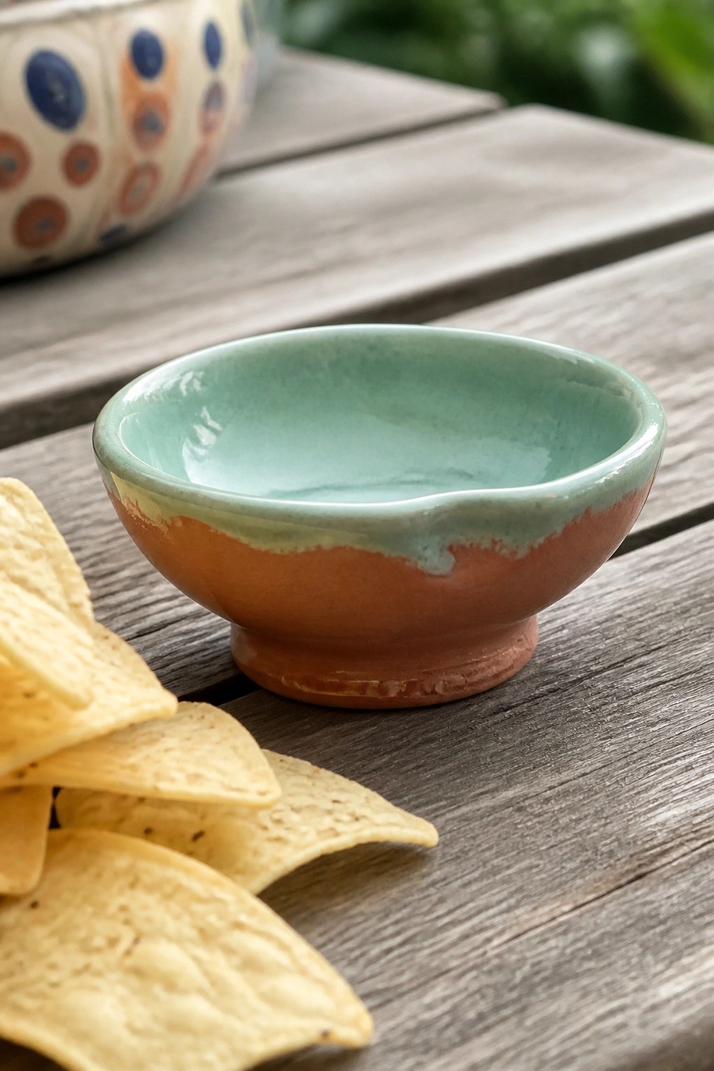 Small turquoise and terracotta ceramic bowl with tortilla chips on wooden table