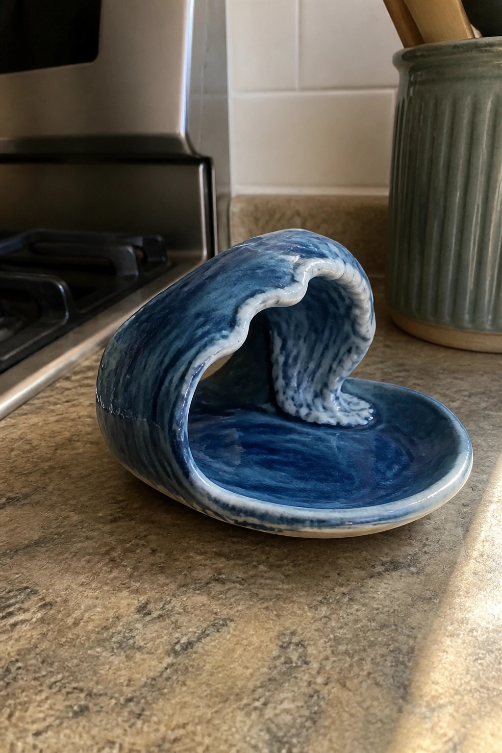 Blue ceramic wave-shaped dish with swirling glaze on granite counter
