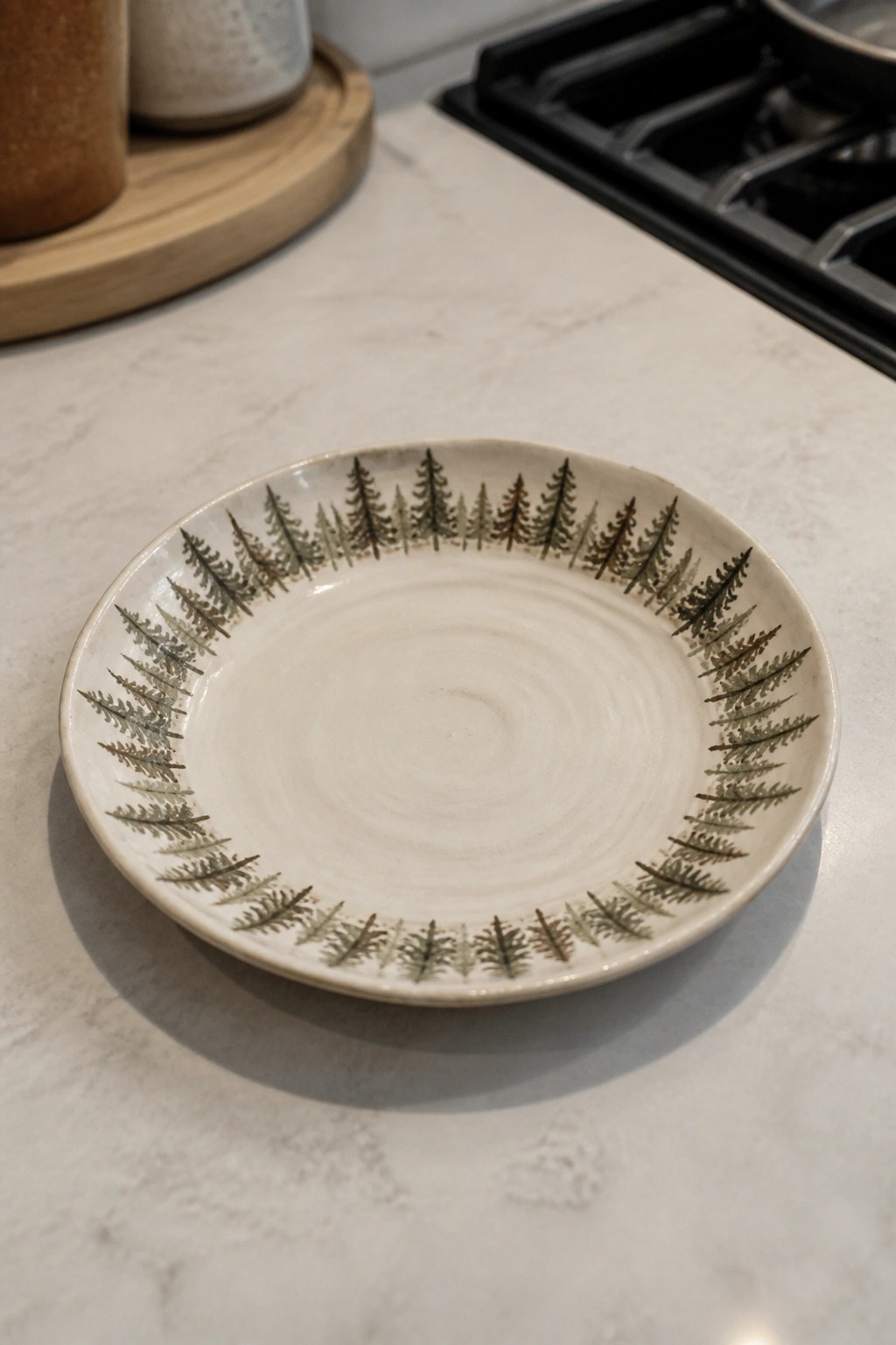 White ceramic plate with pine tree rim on marble kitchen counter