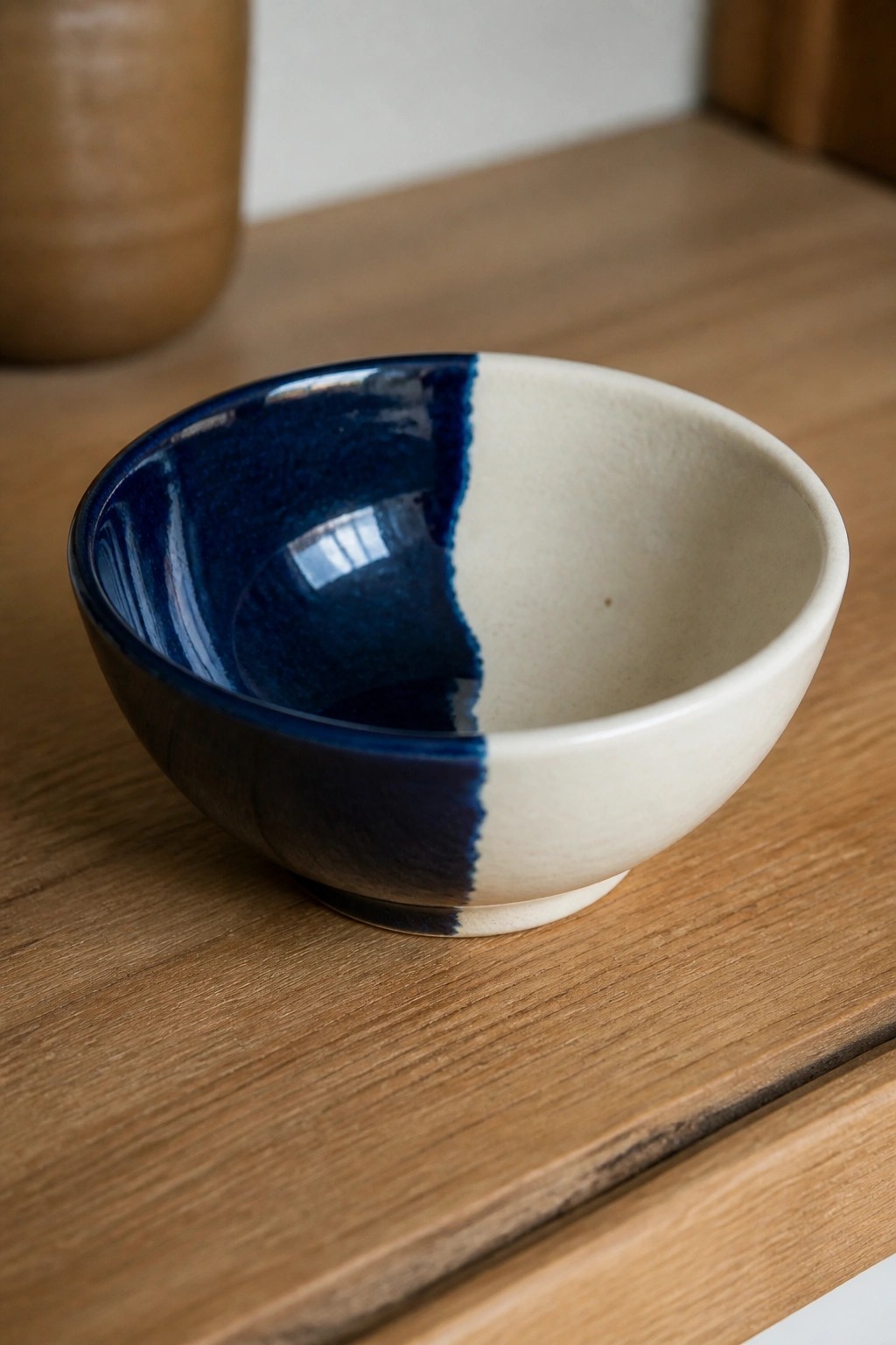 Two-toned blue and cream ceramic bowl on light wooden tabletop