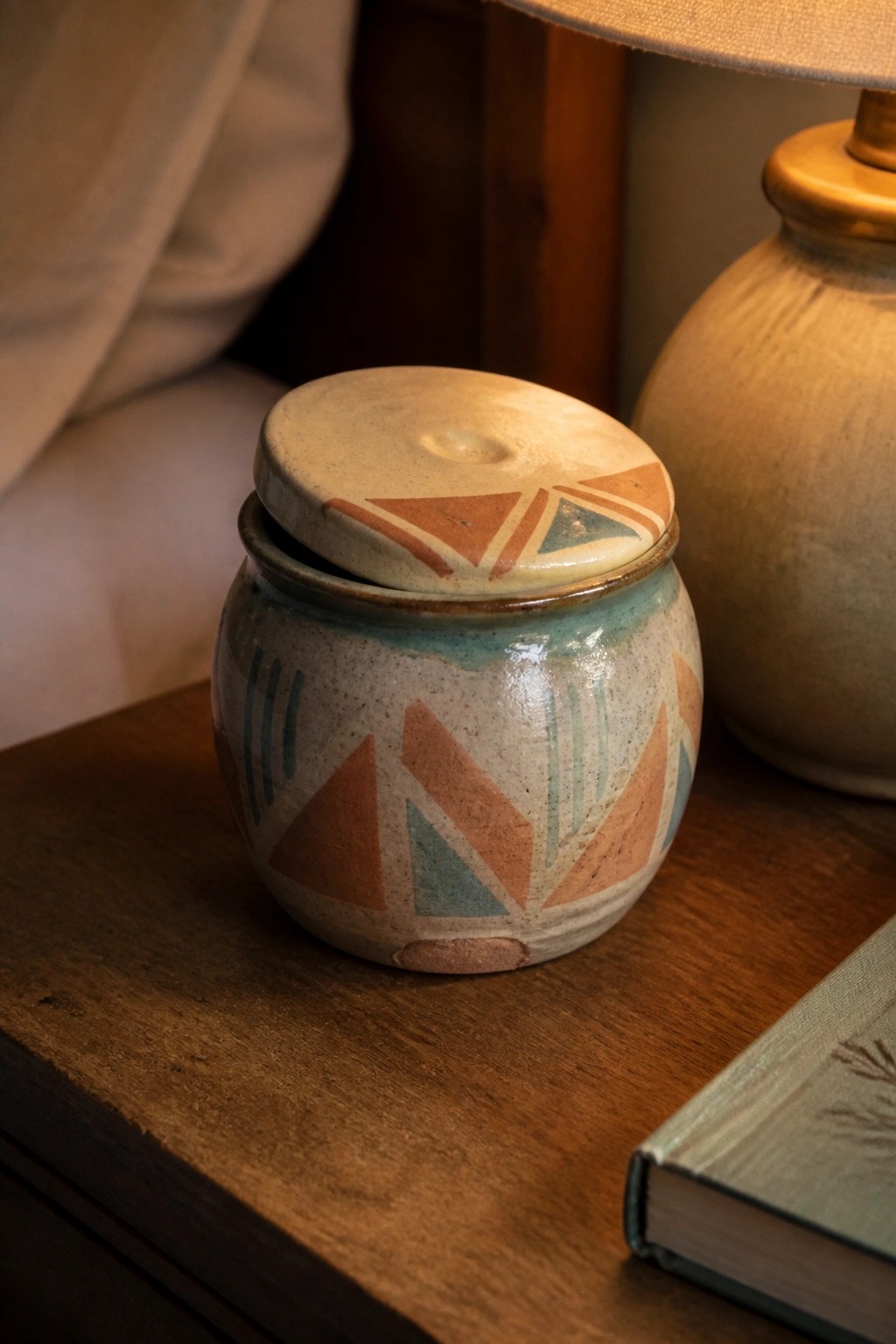 Ceramic lidded jar with orange and teal geometric patterns on wooden table