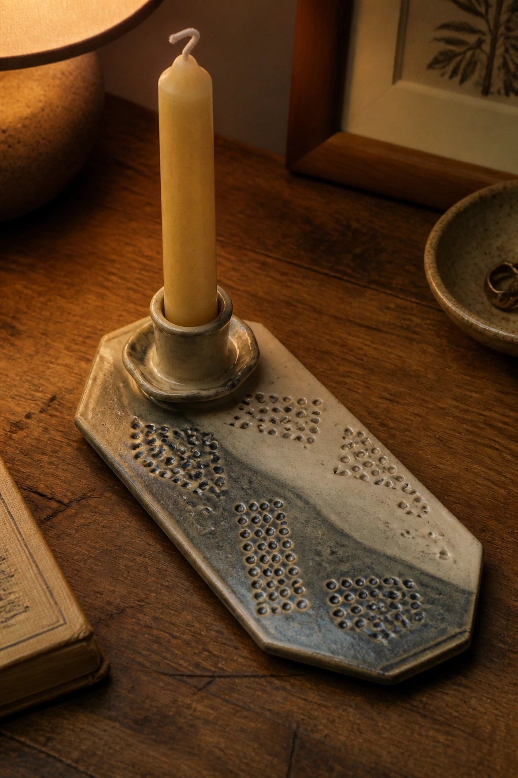 Ceramic candle holder with pale yellow taper and dotted patterns on wooden table