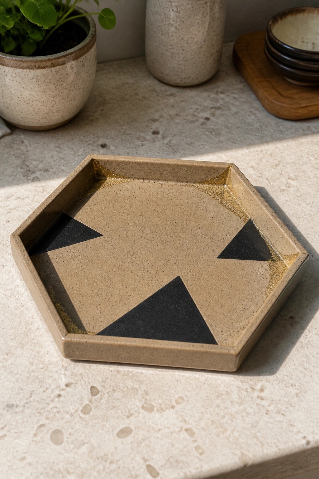 Hexagonal beige tray with black triangles and gold edges on stone countertop