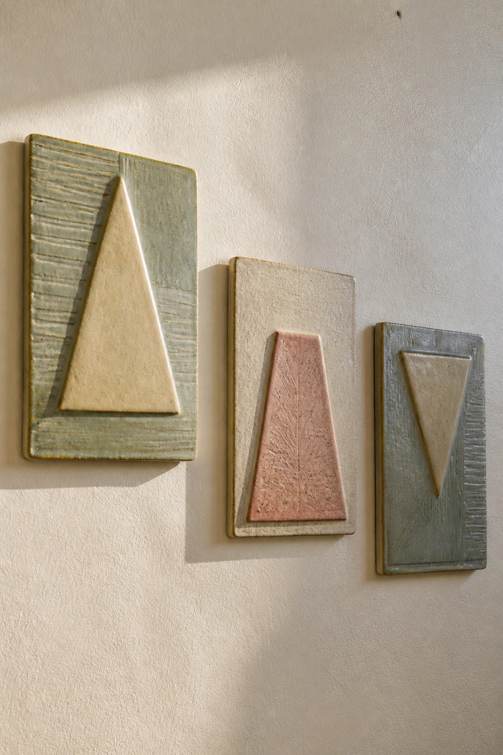 Three rectangular ceramic plaques on wall with textured triangular designs