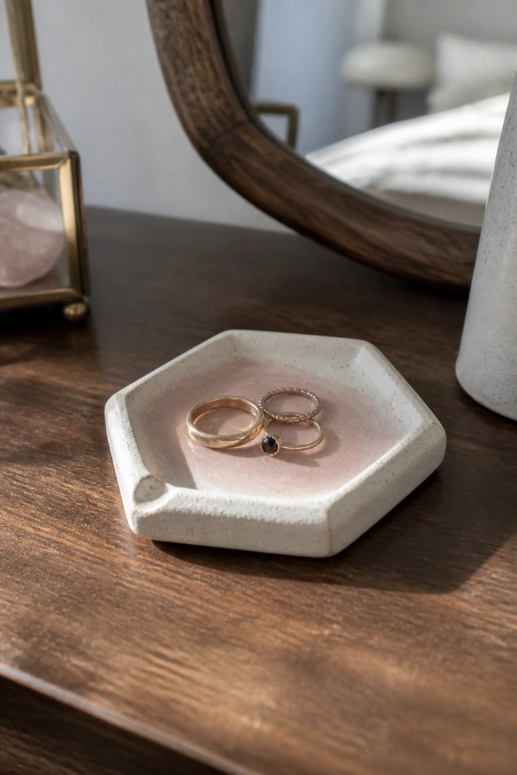 Three gold rings in hexagonal pink ceramic dish on wooden surface