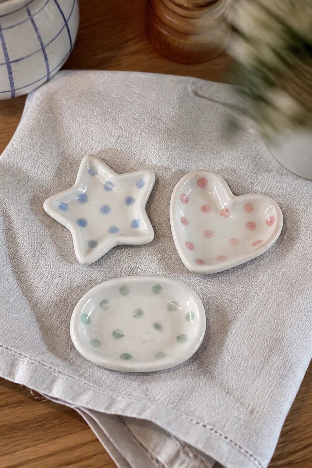 Three polka-dotted ceramic dishes in star, heart, and oval shapes on linen cloth