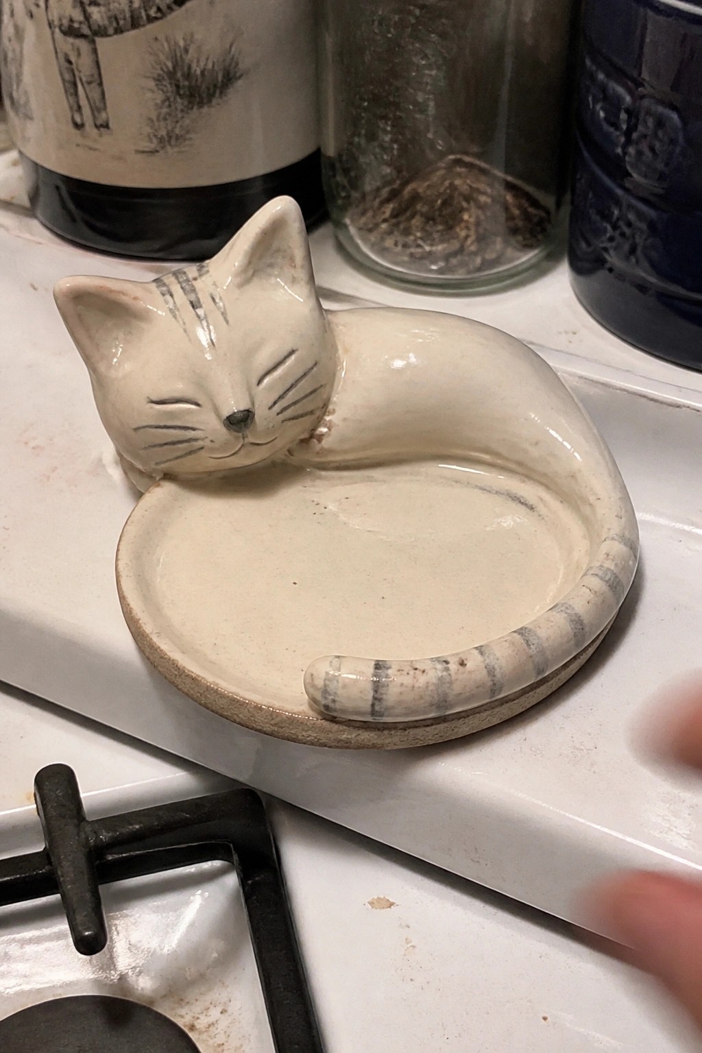 White ceramic sleeping cat dish with striped tail on kitchen counter