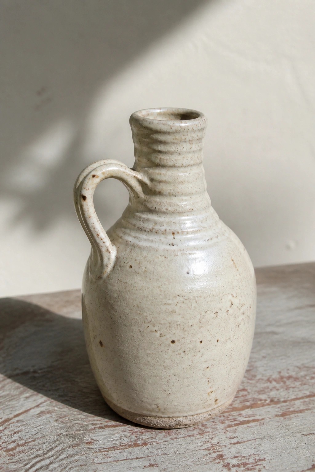 Speckled off-white ceramic jug with handle on rustic wooden table