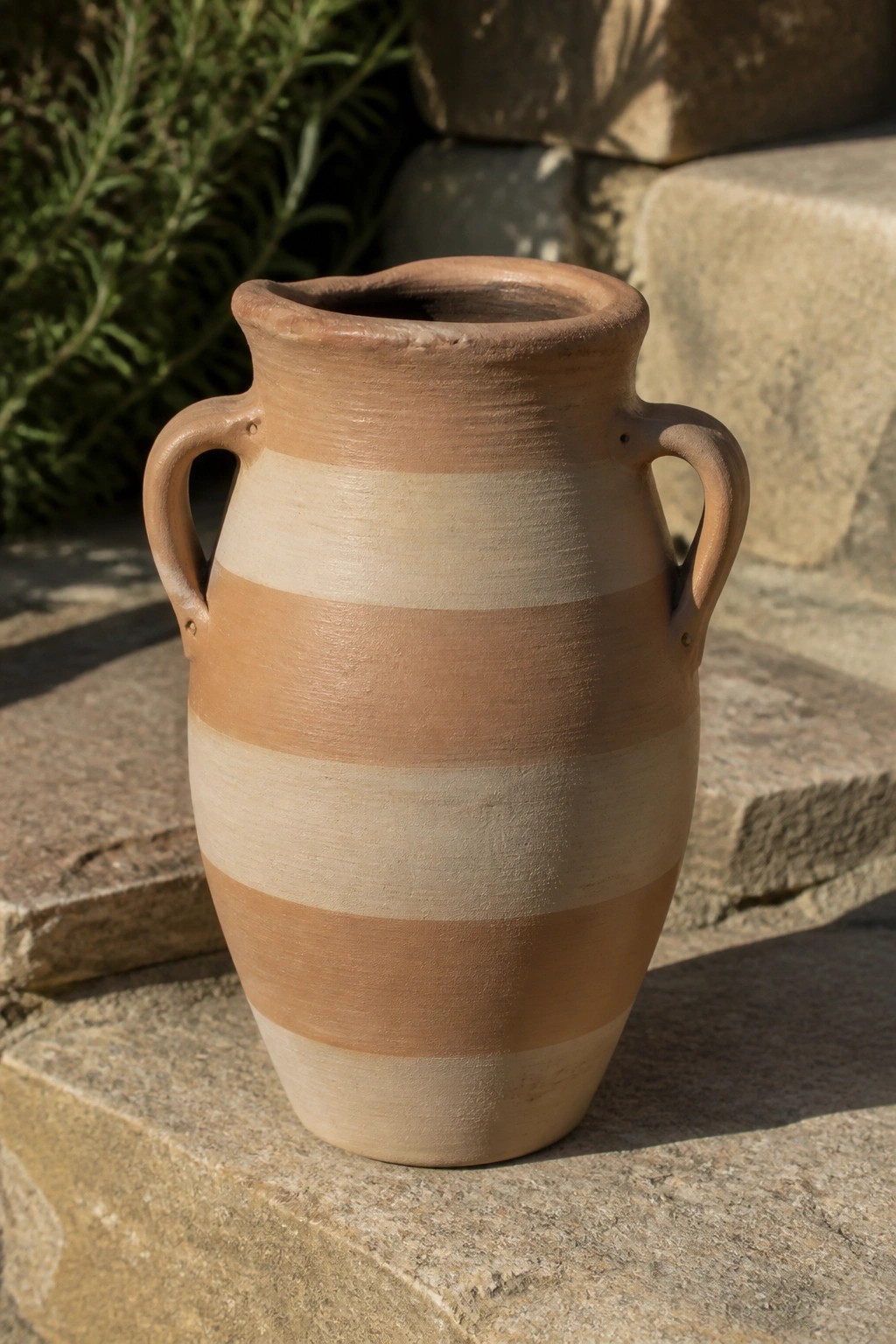 Striped terracotta vase with handles resting on sunlit stone steps