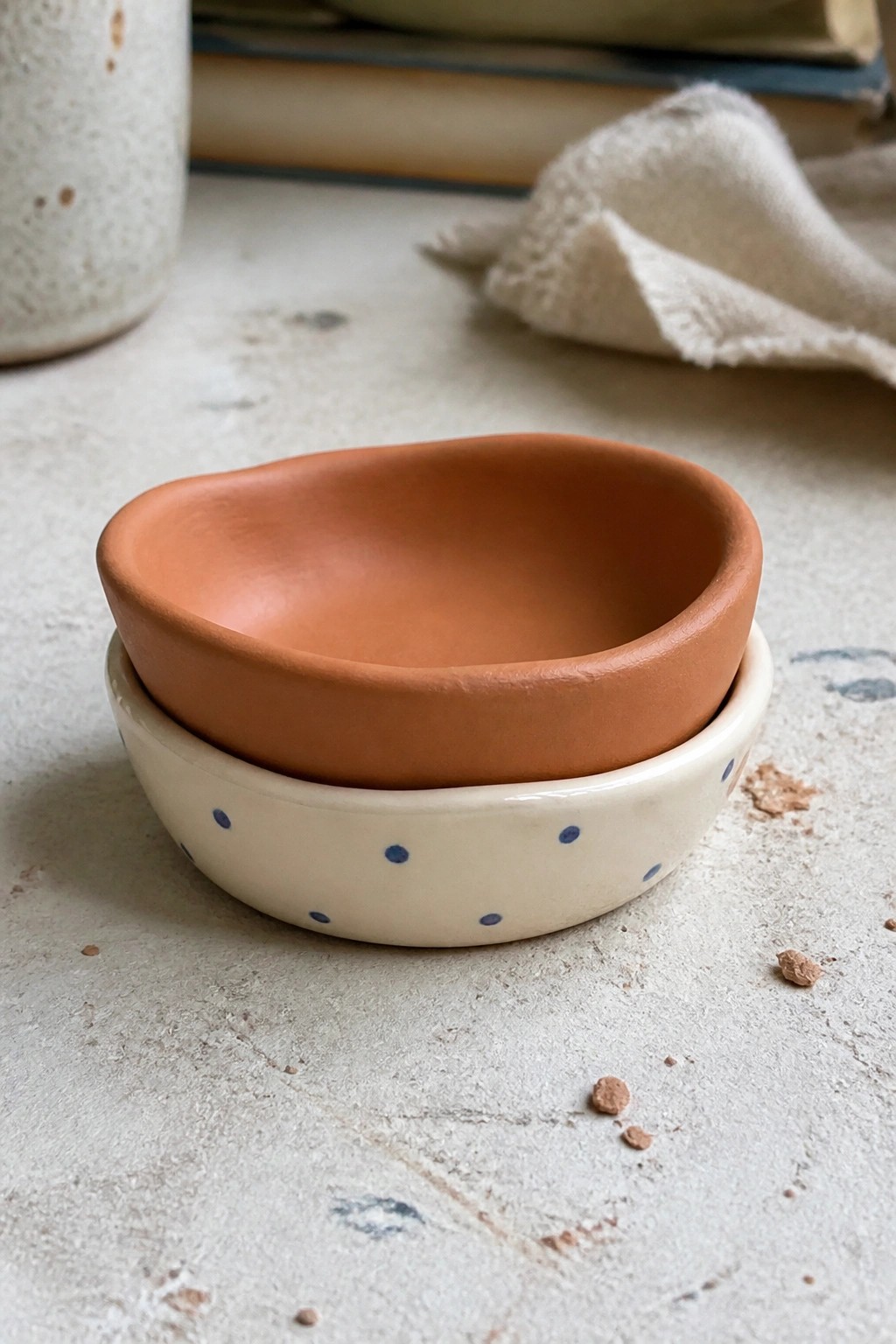 Stacked terracotta bowl atop white ceramic bowl with blue polka dots