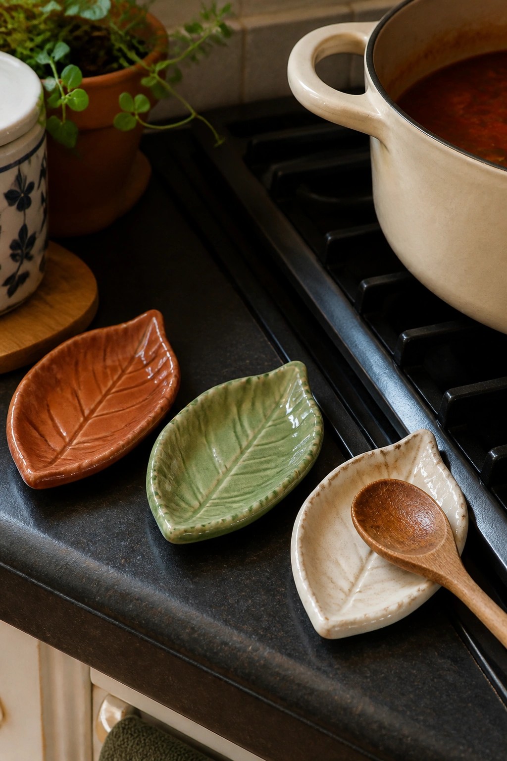 Three leaf-shaped ceramic dishes with spoon beside pot of red soup on stove.