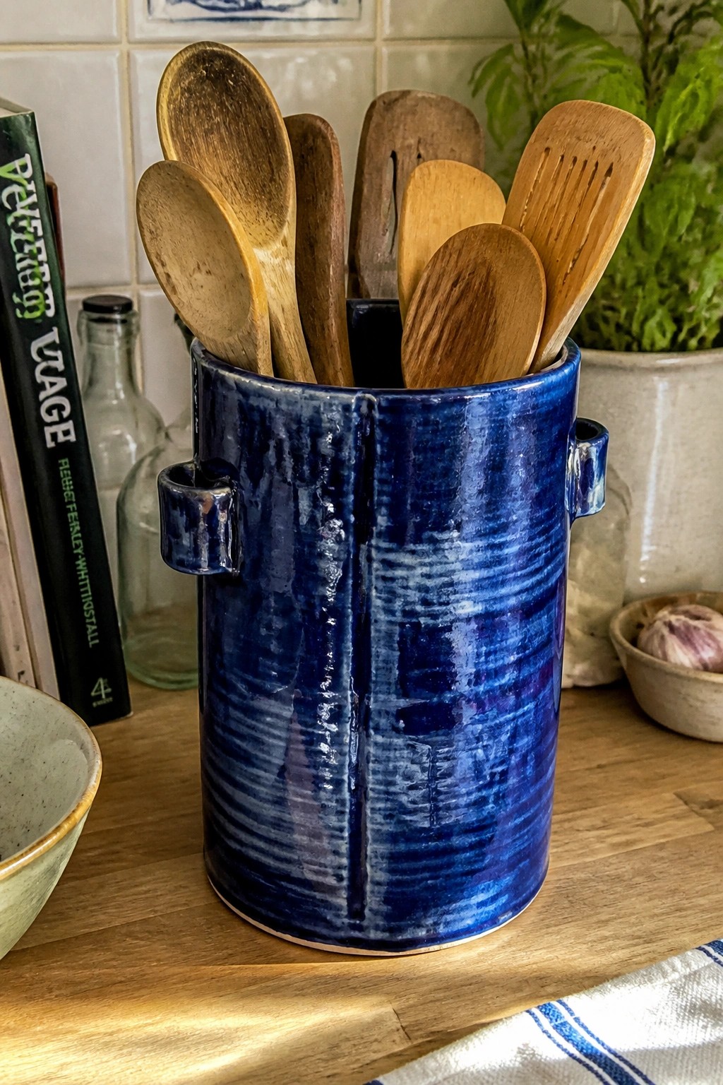 Blue ceramic crock brimming with wooden spoons and spatulas on kitchen counter