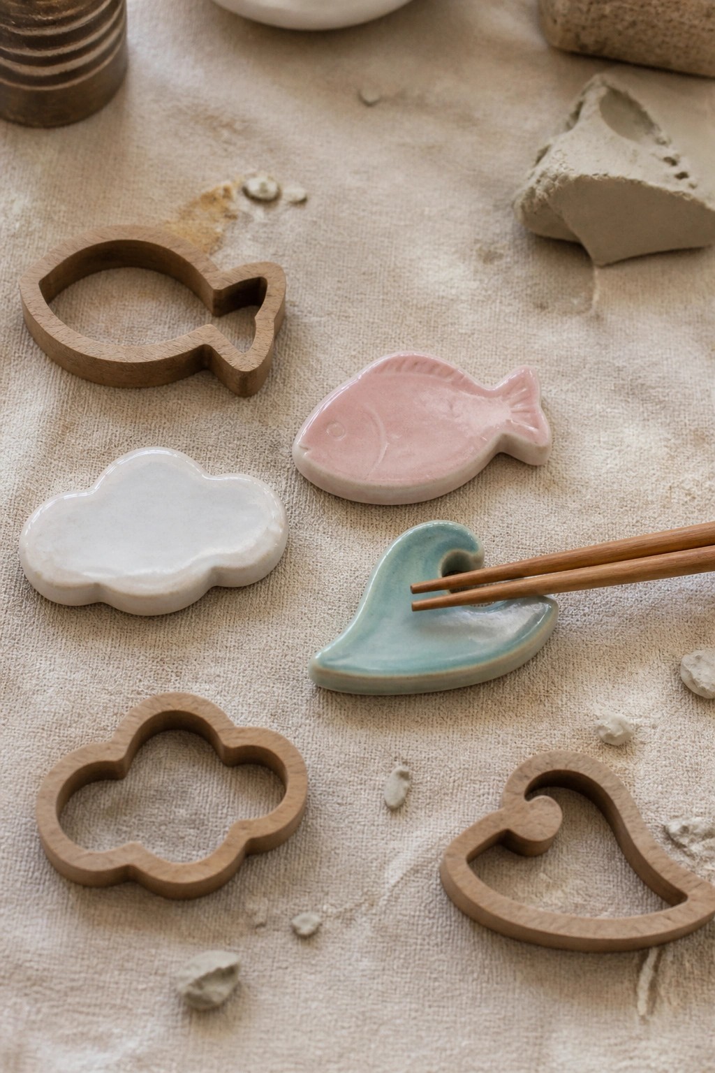 Wooden fish, cloud, heart cutters with ceramic fish, cloud, wave on beige fabric.
