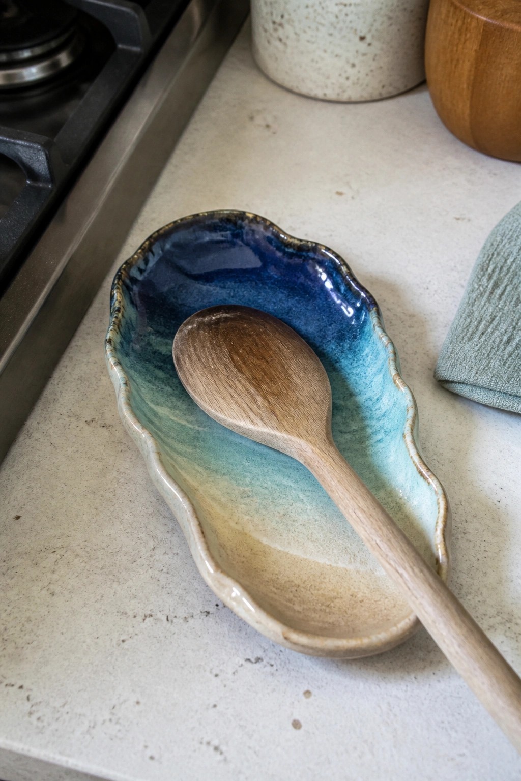 Wooden spoon resting in blue-green glazed ceramic dish on kitchen counter