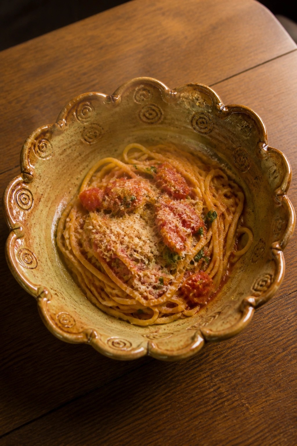Spaghetti with tomato sauce and cheese in an ornate scalloped ceramic bowl