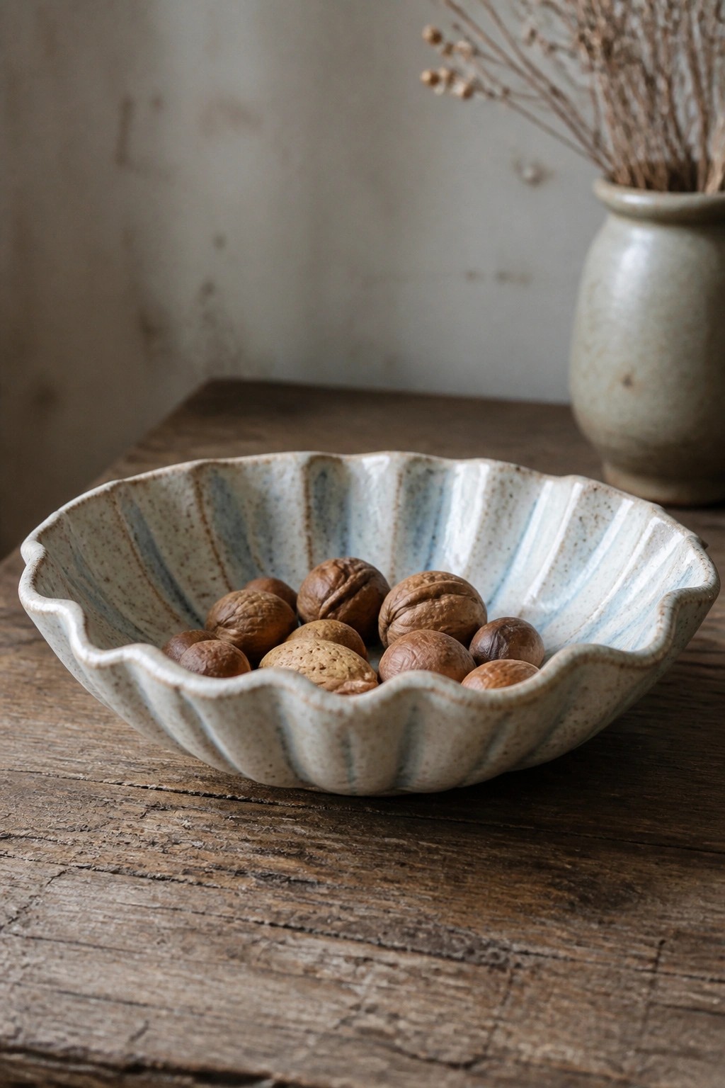 Scalloped ceramic bowl with blue glaze holding mixed nuts on wood
