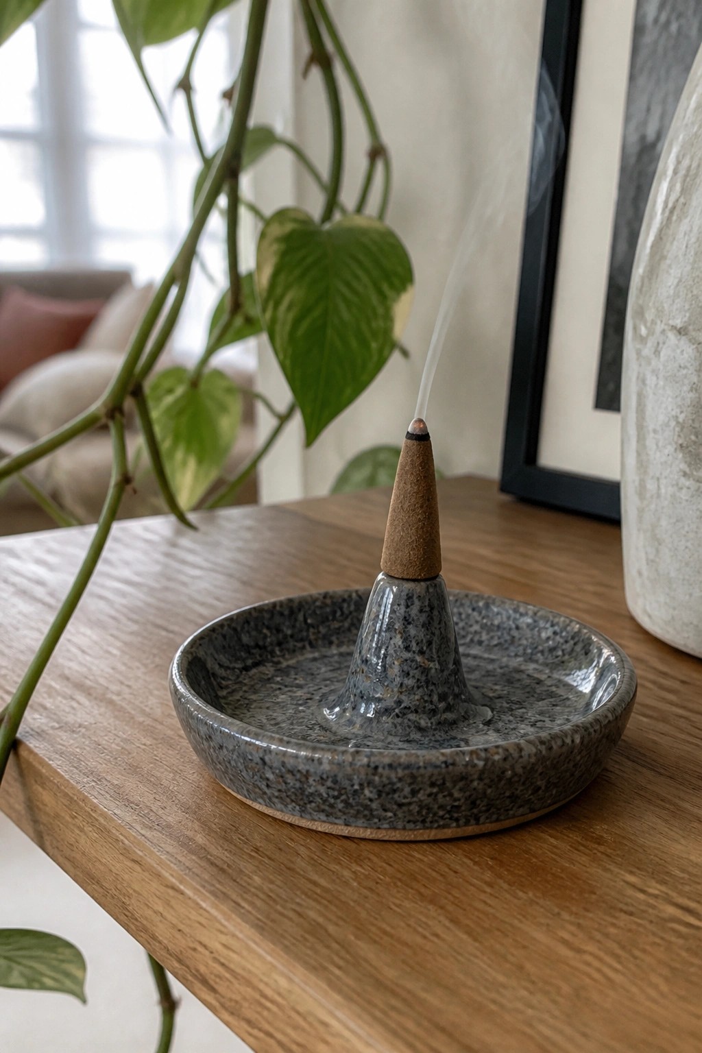 Burning brown incense cone in a speckled ceramic holder on wooden table.