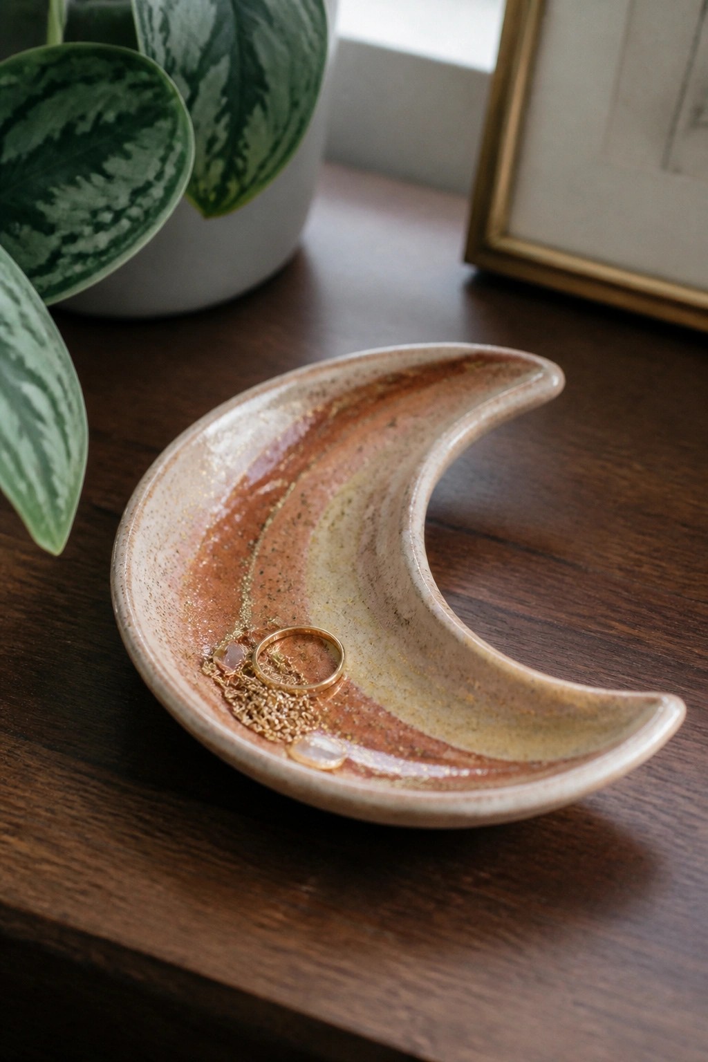 Earth-toned crescent moon ceramic dish holding gold ring and crystals on wood