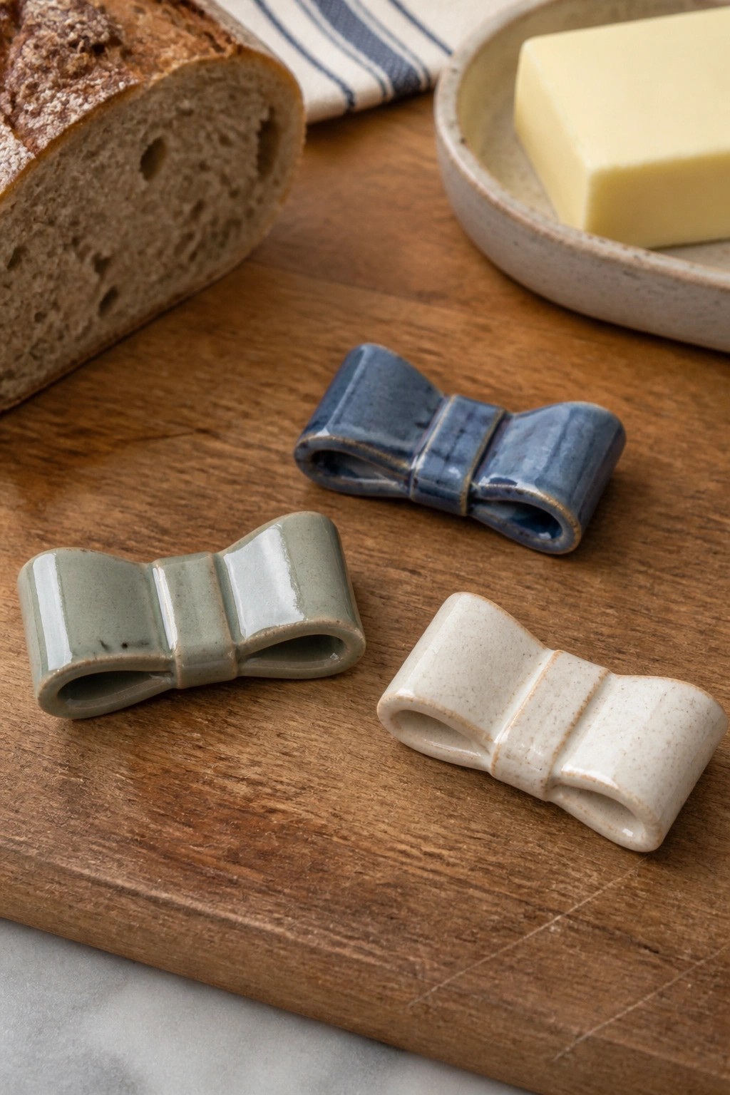 Three ceramic bows in blue, green, and white on wooden board with bread and butter.