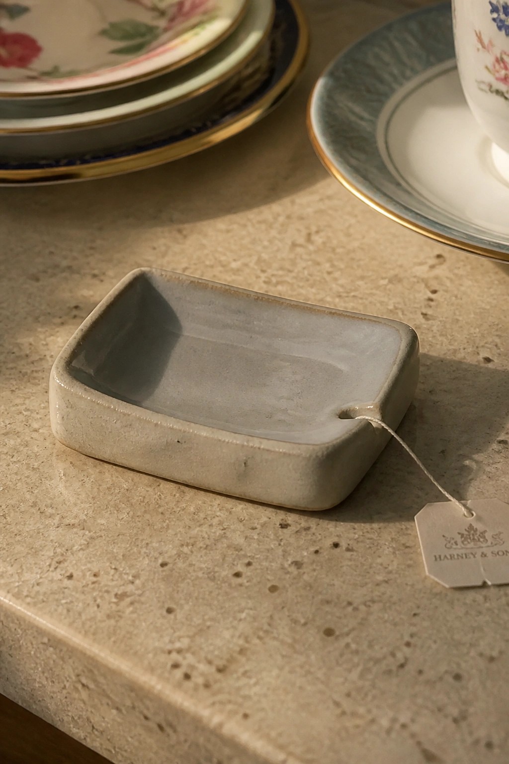 Small gray ceramic dish with Harney & Sons tag on marble surface