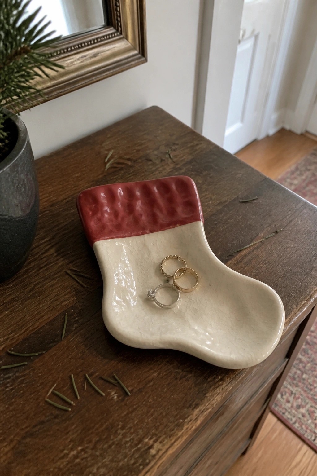 Red and white Christmas stocking dish holding three rings on wooden table
