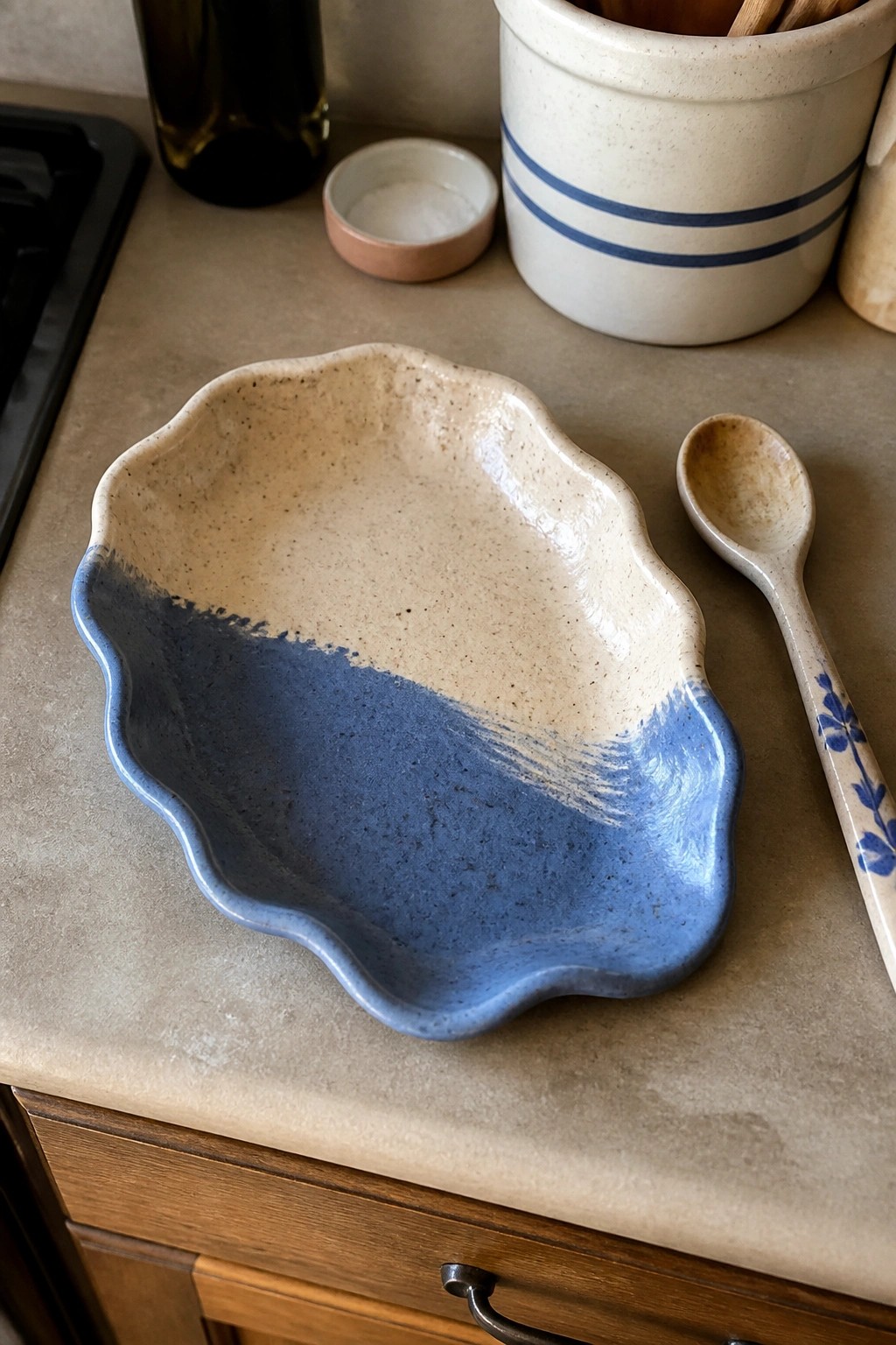 Speckled blue and beige ceramic bowl with wavy rim beside floral spoon on counter