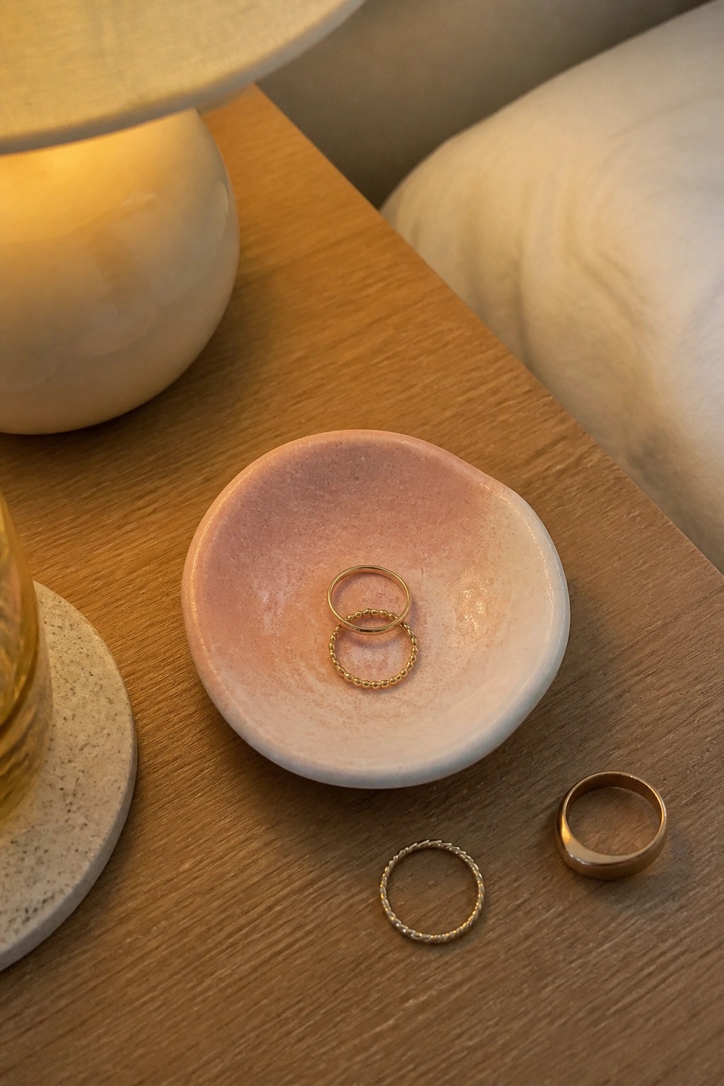 Gold rings inside a pink bowl and beside it on a wooden table