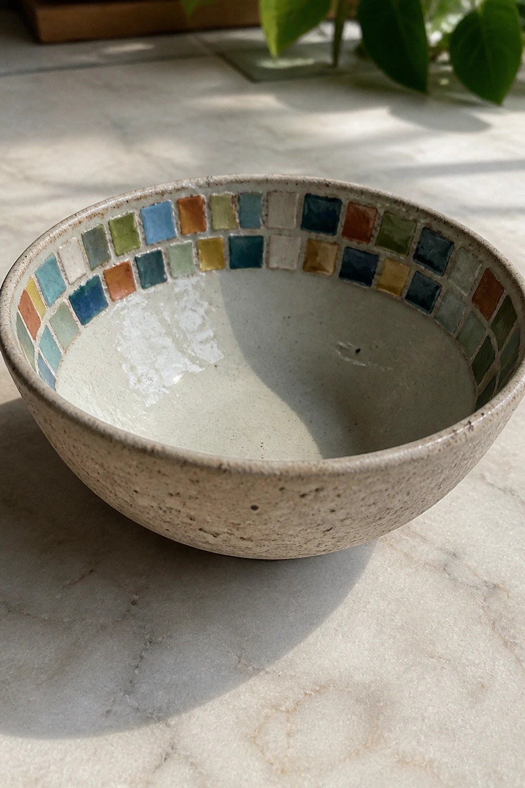 Ceramic bowl with colorful mosaic tile rim on white marble surface
