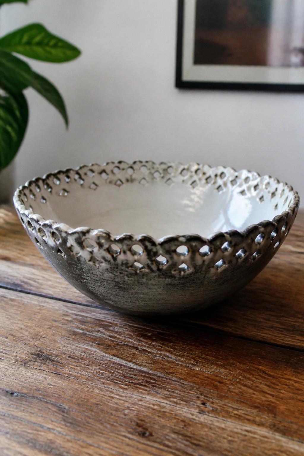 Mottled gray ceramic bowl with scalloped perforated rim on wooden table