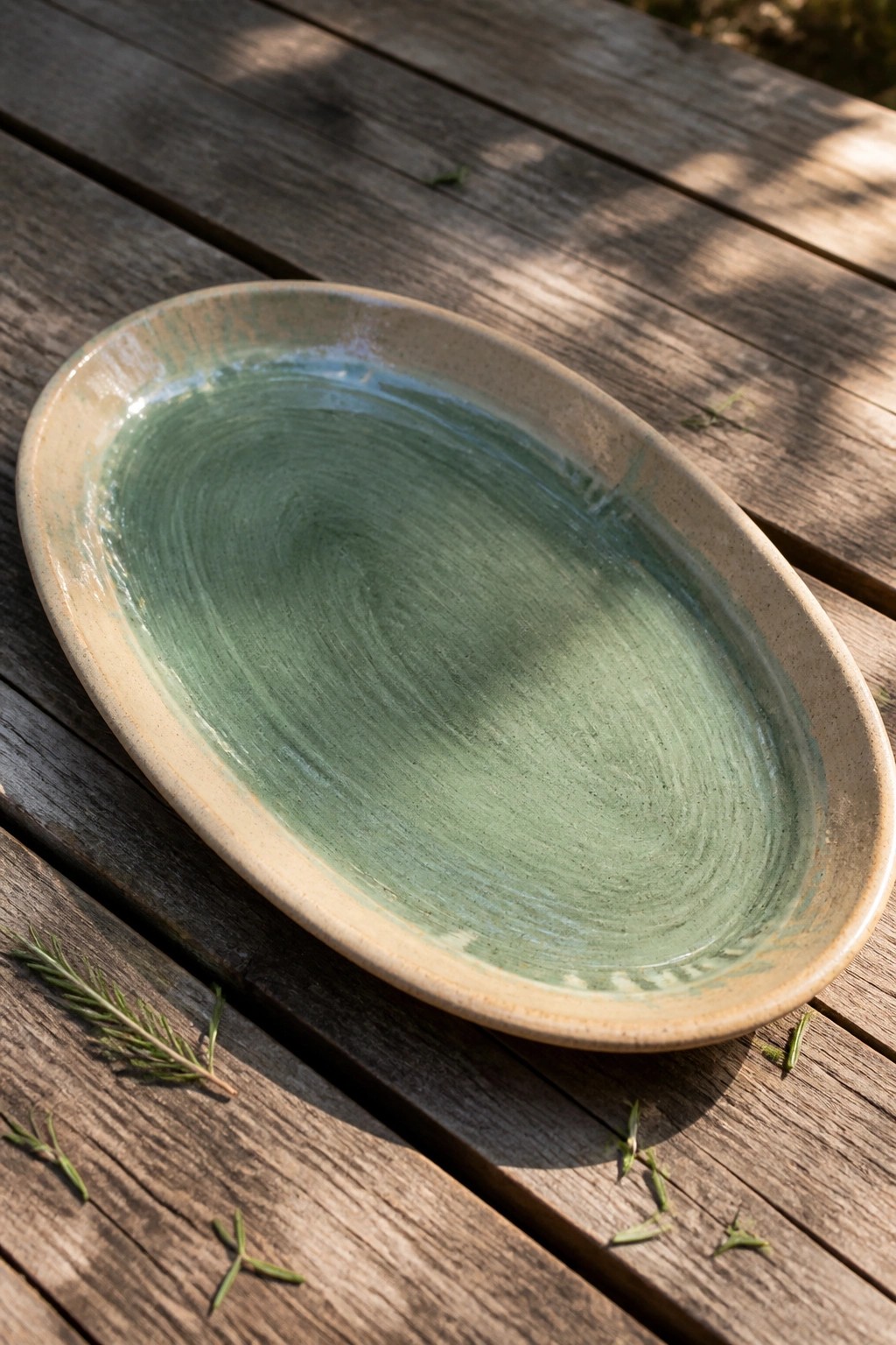 Green-swirled ceramic platter on wooden table with rosemary sprigs
