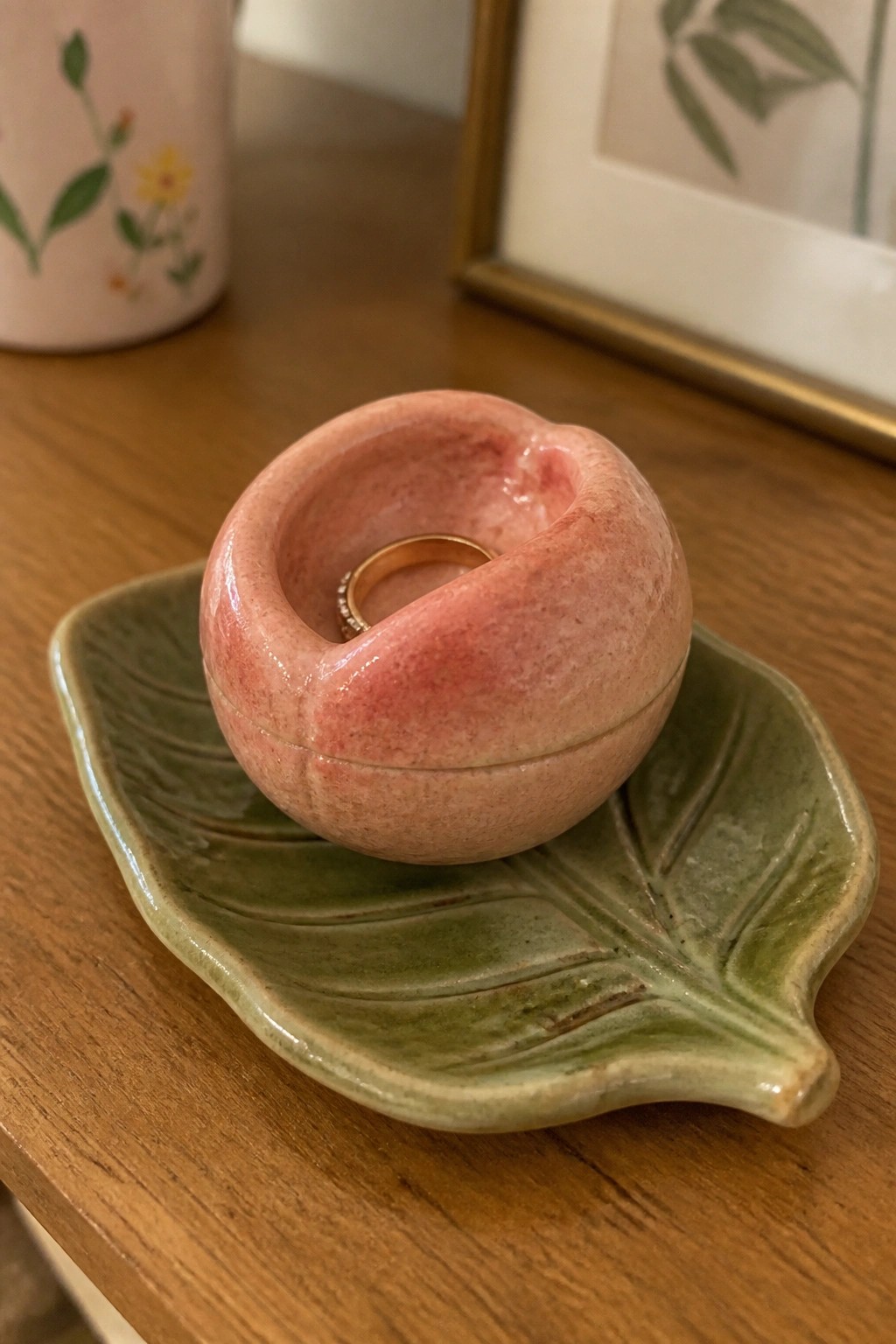 Pink glossy peach ceramic holder with gold ring on green leaf dish