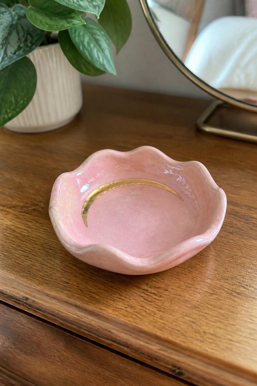 Pink scalloped ceramic bowl with gold crescent moon on wooden dresser
