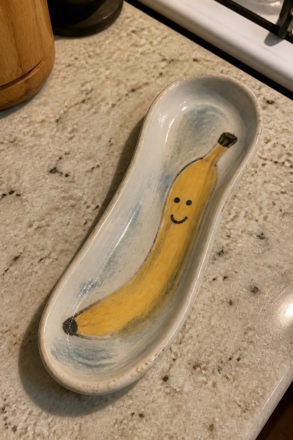 White ceramic dish with smiling yellow banana painted on speckled countertop