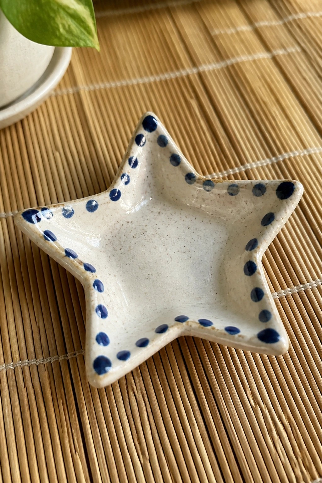 Star-shaped white ceramic dish with blue dots on bamboo mat