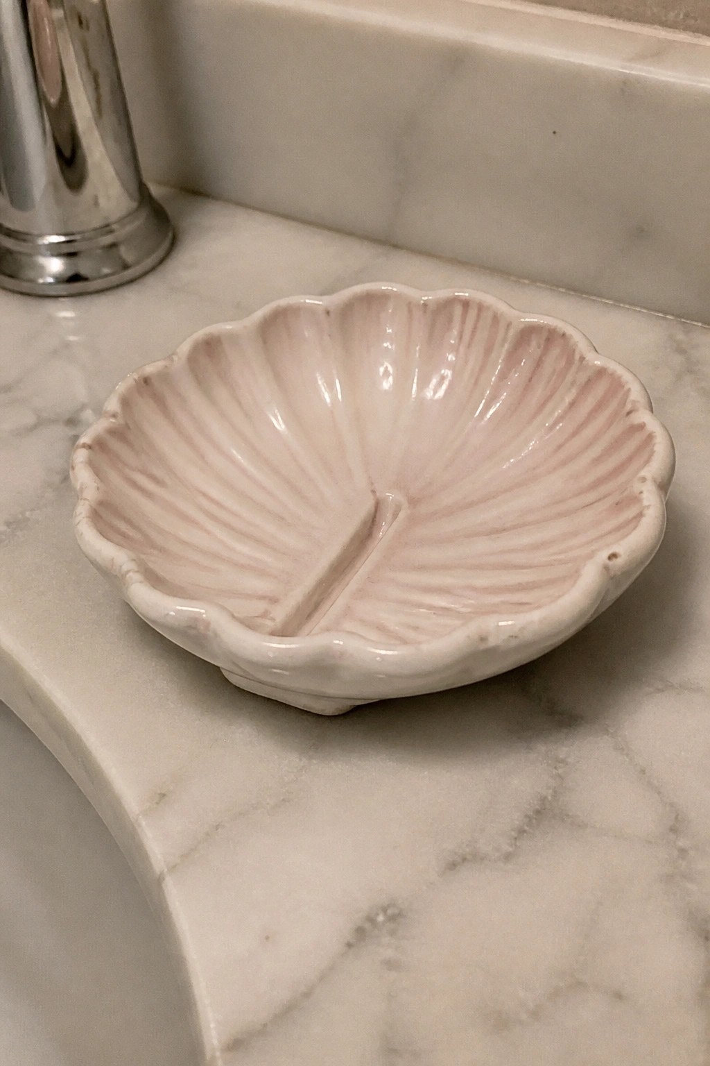 Pink shell-shaped ceramic dish with divider on marble countertop