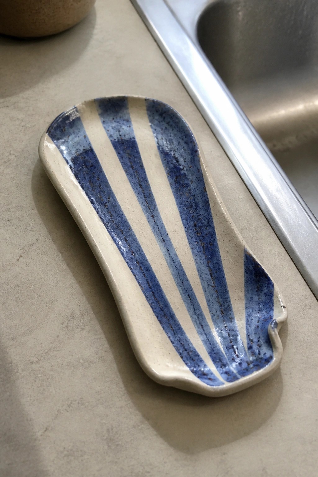 Blue striped ceramic dish on kitchen countertop beside stainless sink