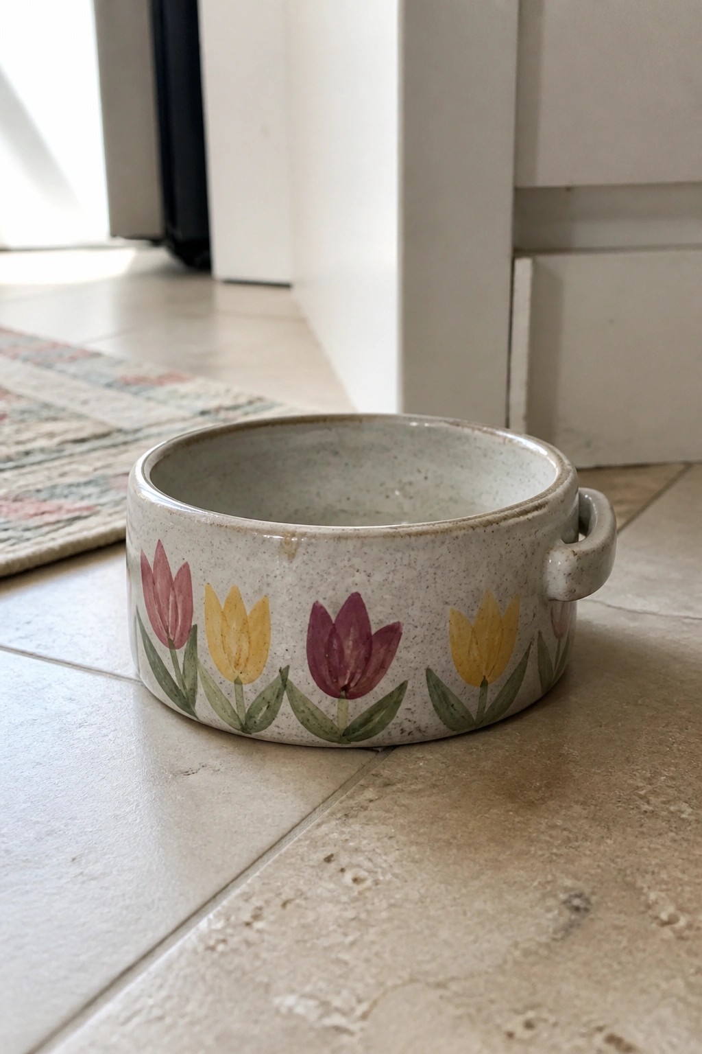 Ceramic bowl with pink, yellow, and purple tulips on tiled floor