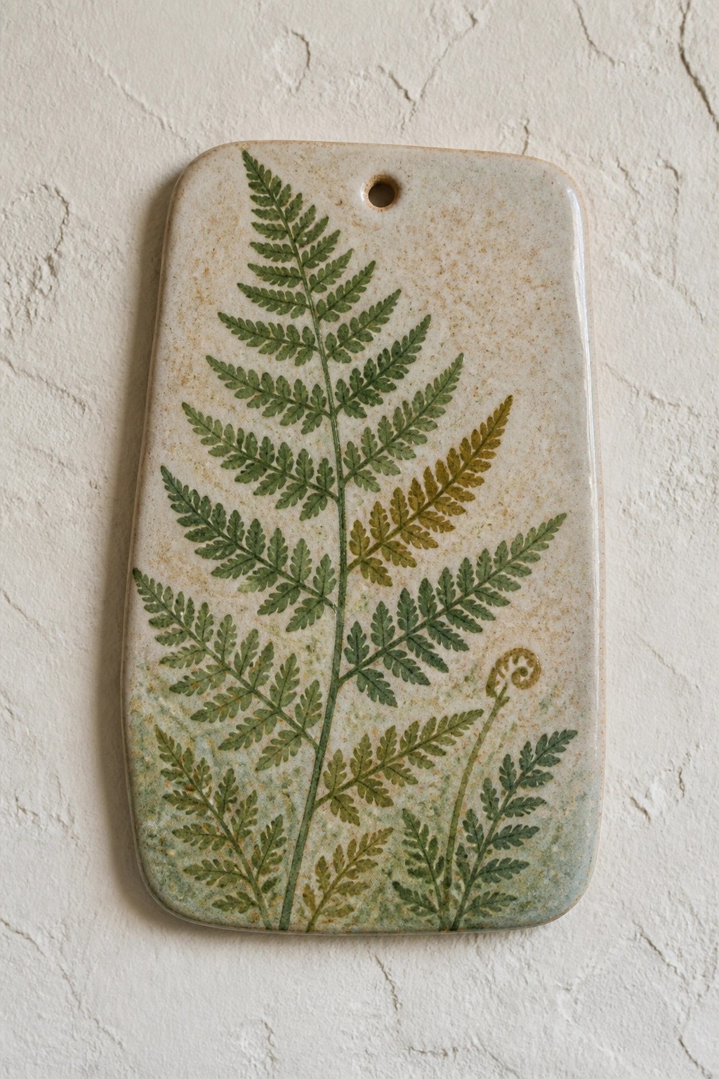 Rectangular ceramic plaque with green fern leaf prints on white wall