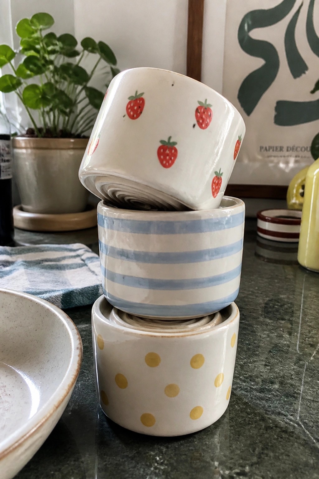 Three stacked ceramic bowls with strawberry, blue stripe, and yellow polka dot patterns on counter