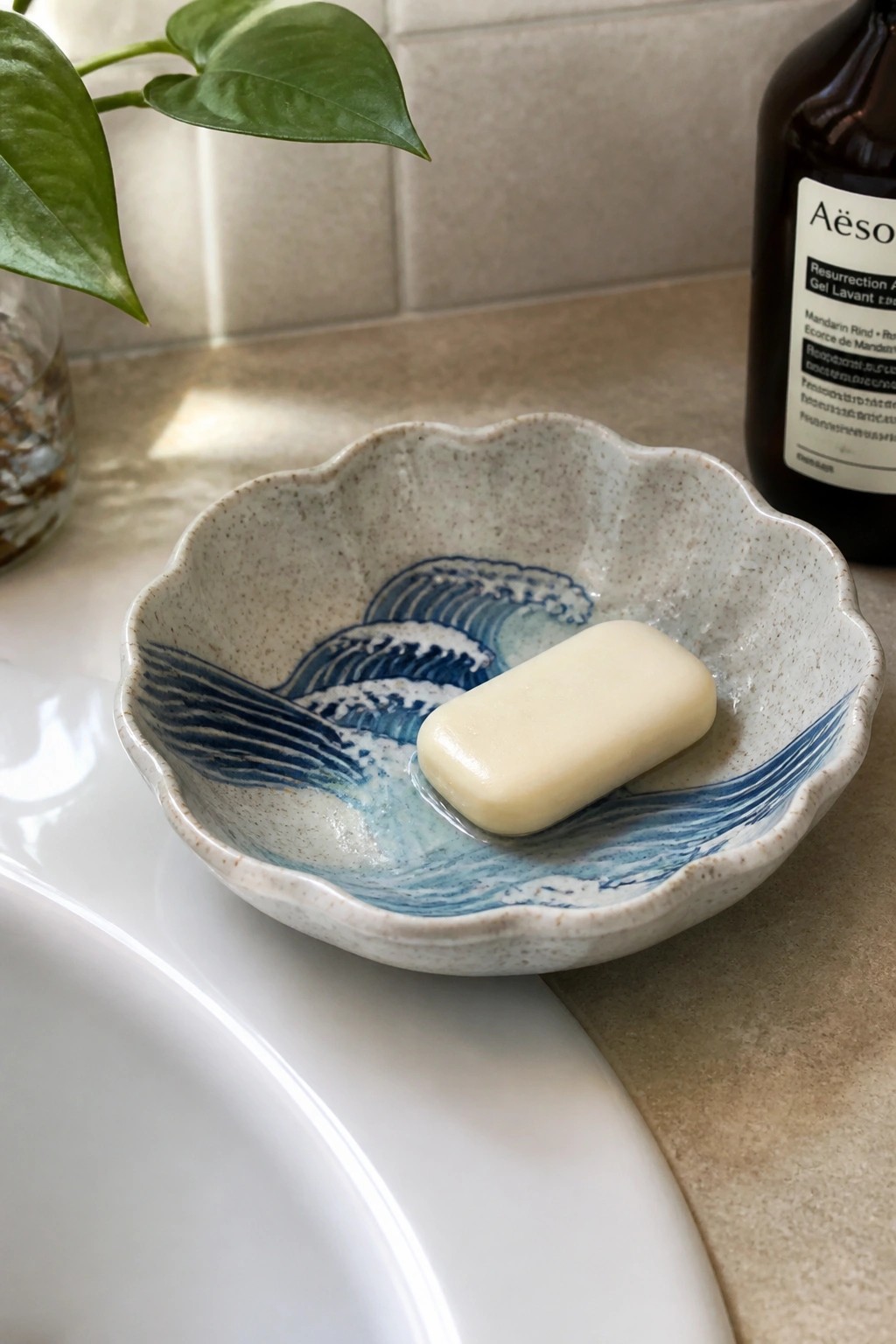 Ceramic soap dish with blue wave design holding pale yellow bar on bathroom sink.