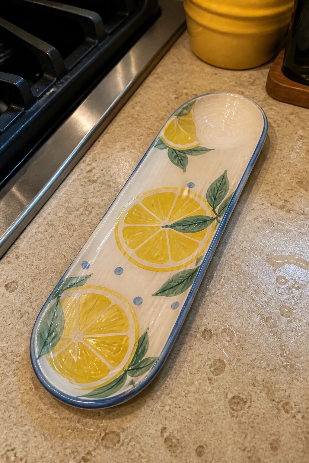 Oval ceramic dish with yellow lemons, green leaves, and blue rim on countertop