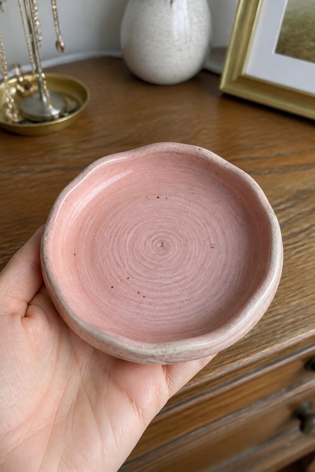 Hand holding pink ceramic bowl with spiral pattern on wooden table