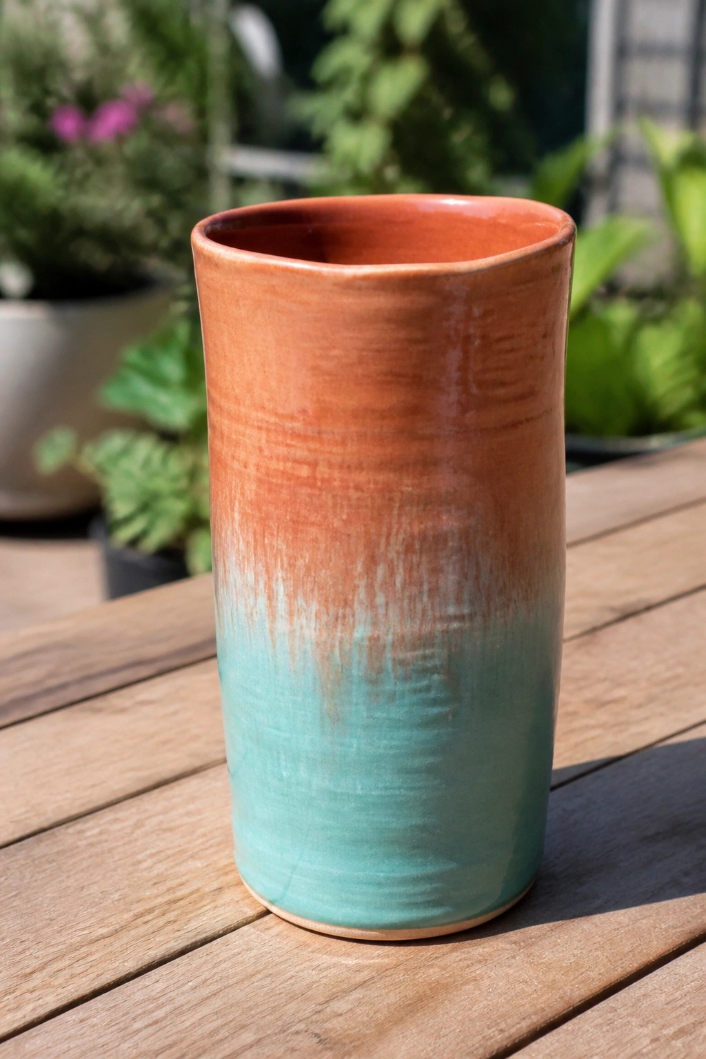 Gradient ceramic vase with orange top fading to turquoise on wooden table