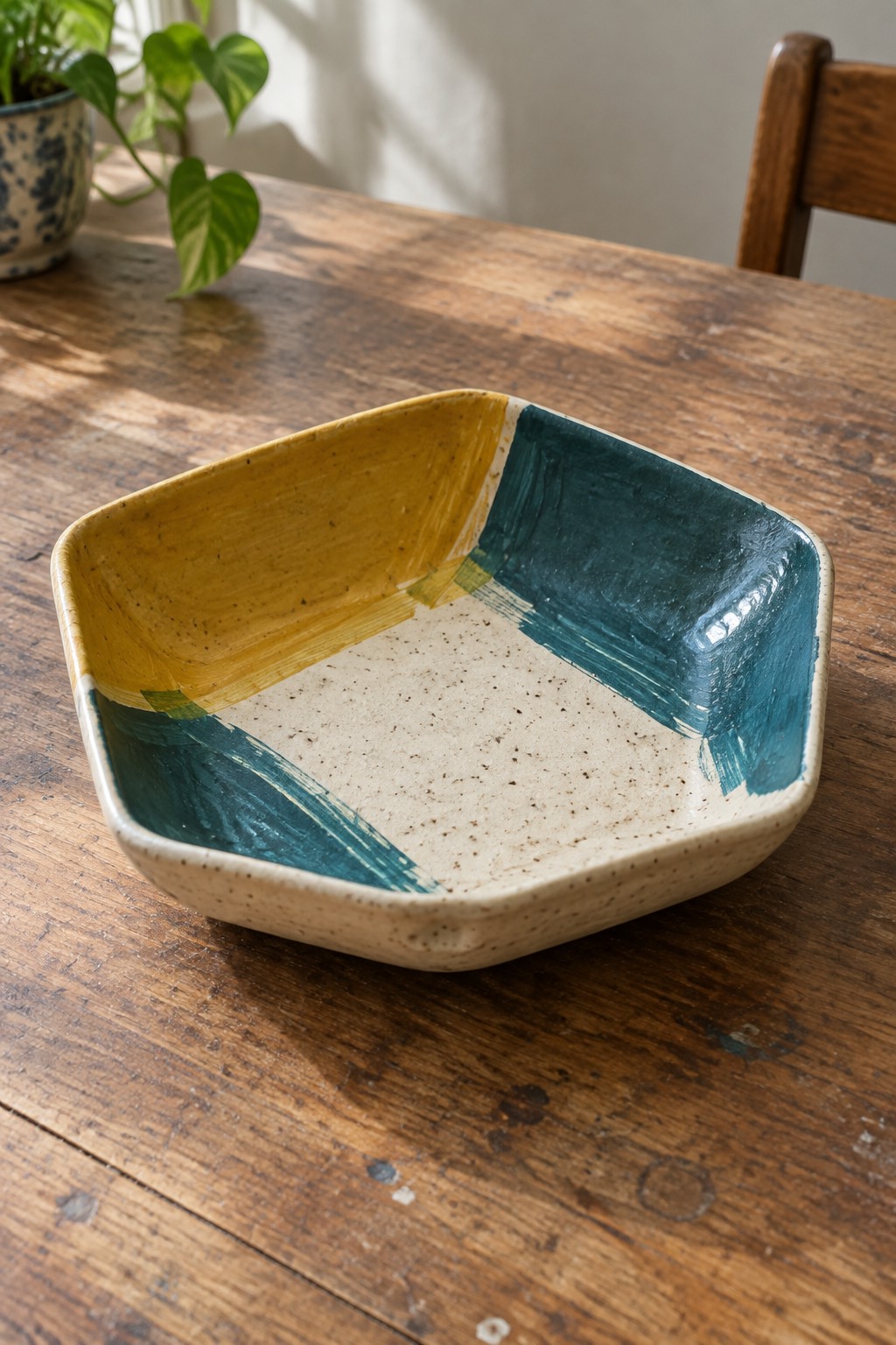Square ceramic bowl with yellow, teal and cream brushstrokes on wooden table