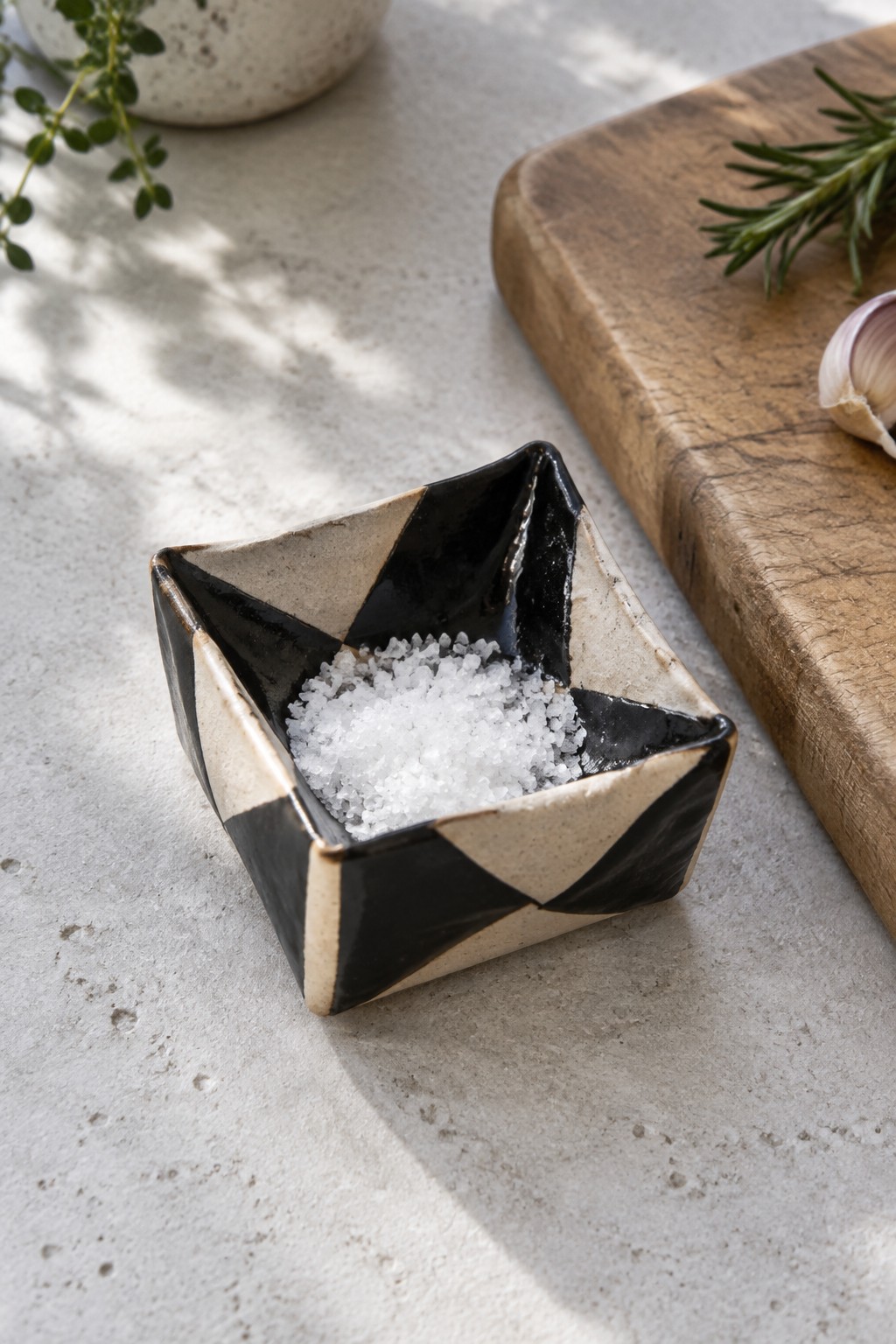 Black and beige geometric ceramic bowl filled with white salt on gray surface